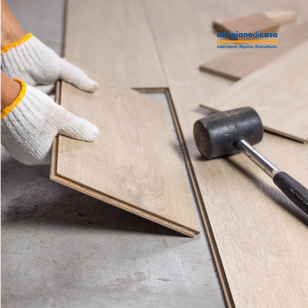 Posa pavimento effetto legno, mani con guanti allineano una doga mentre un martello in gomma e altre doghe sono sul pavimento.